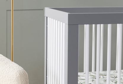 Close-up view of a stylish gray baby crib in a nursery with a cream blanket visible on the side.