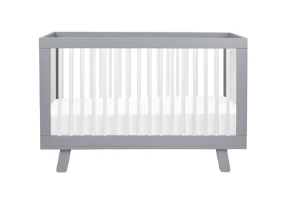 Gray modern crib with a white mattress on a neutral background.