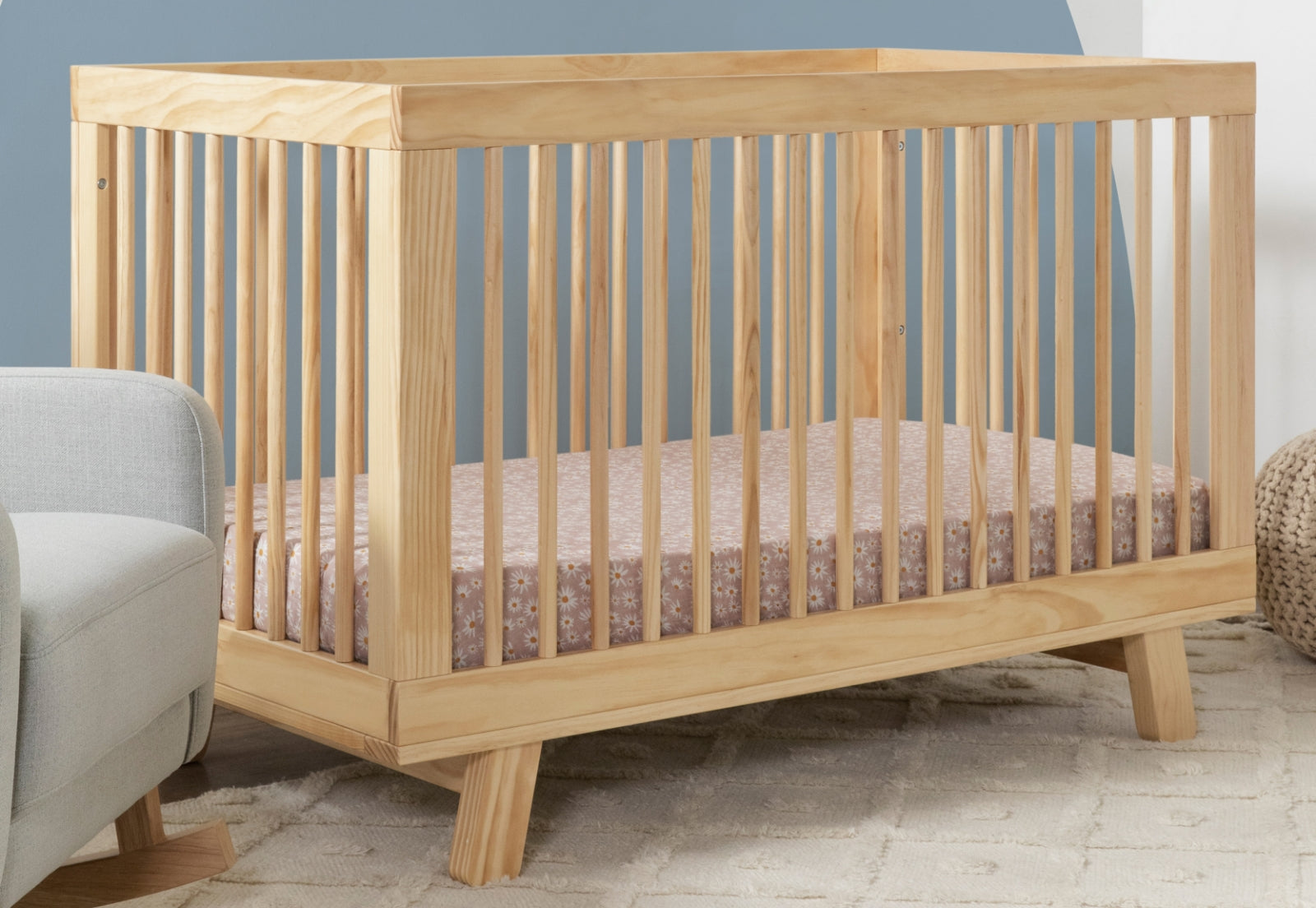 A natural wood baby crib in a serene nursery room setting.