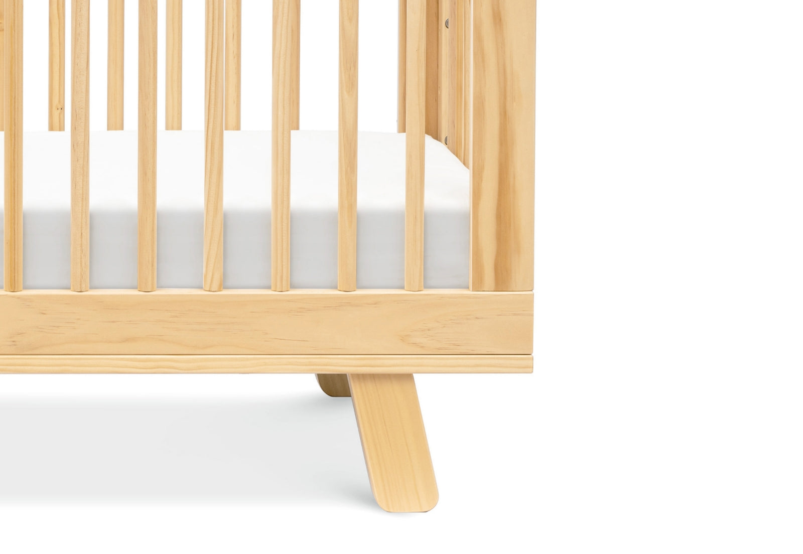 Close-up view of the corner of a modern wooden baby crib with a visible mattress.