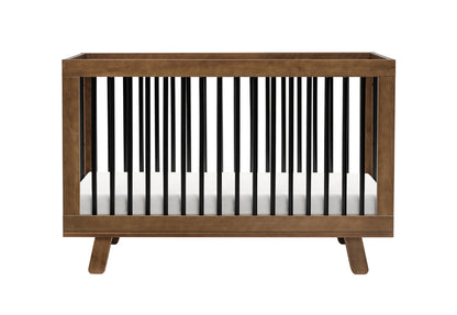 A modern baby crib with dark wooden frame and contrasting black spindles, set against a white background. 999-8501-NWB
