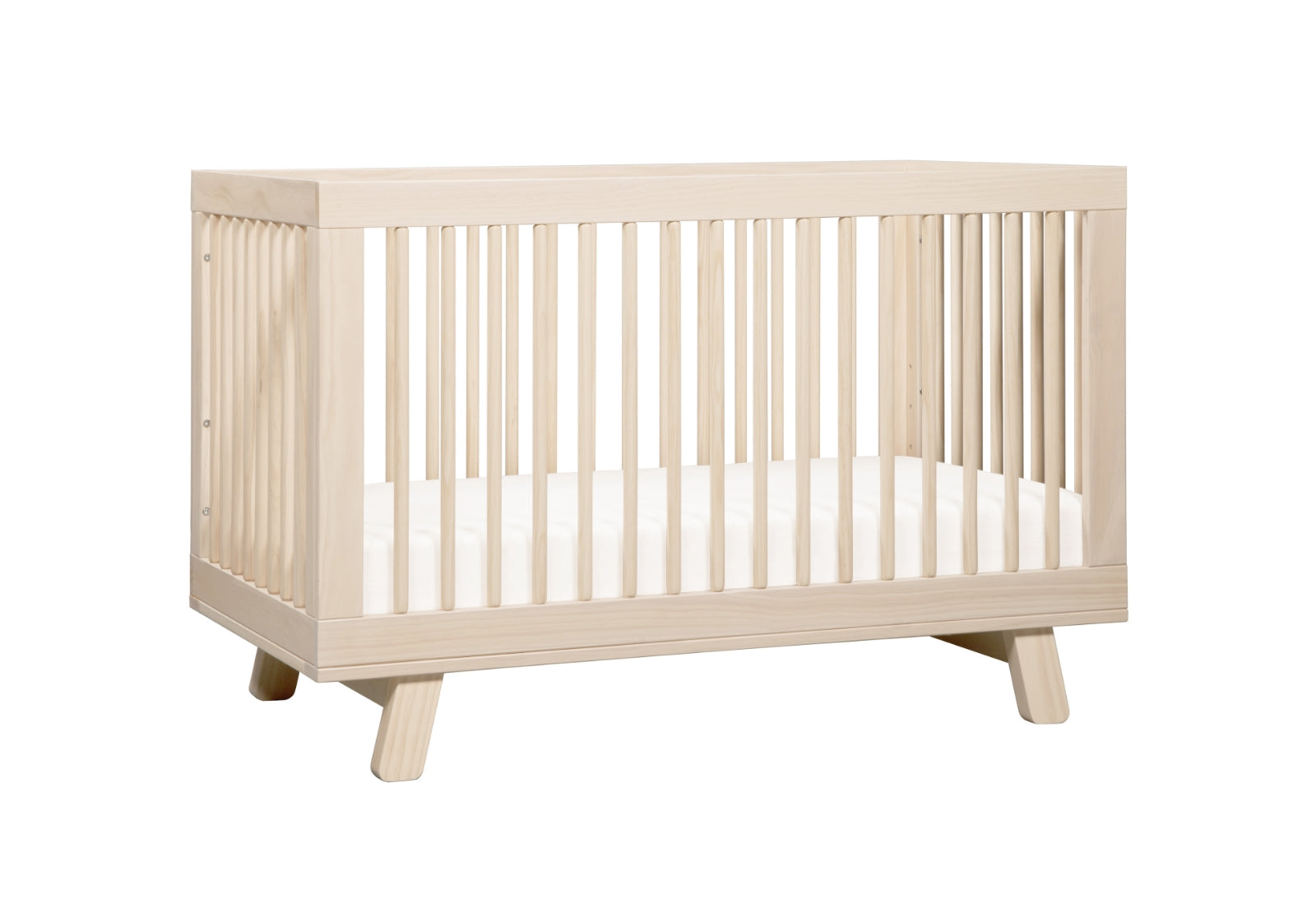 Alt text: "Light wood baby crib with visible grain and angled legs, featuring vertical slats on all sides."