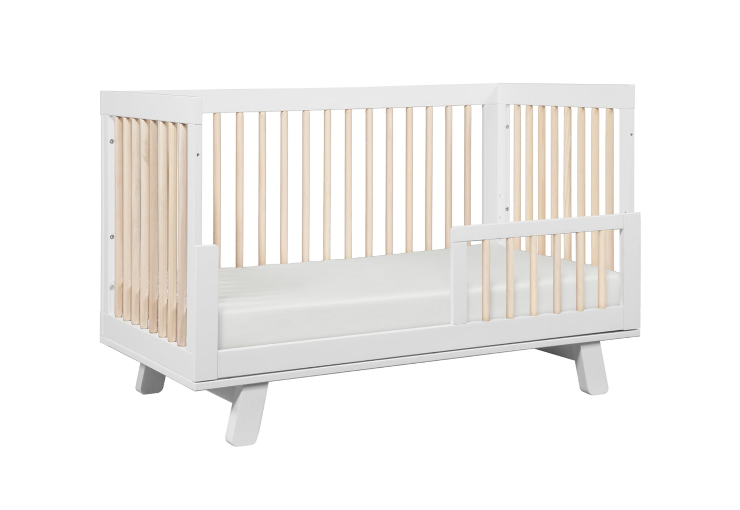 A modern white crib with a slatted design on all sides, set against a plain background.