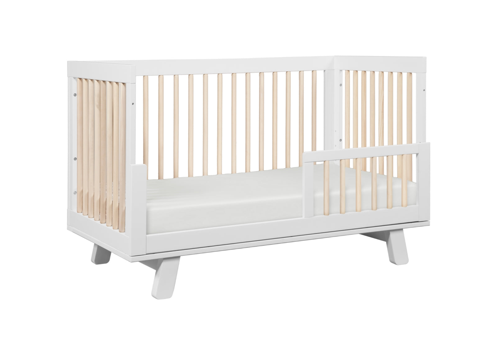 A modern white crib with a slatted design on all sides, set against a plain background.