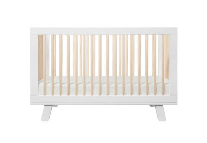Modern white baby crib with a slated design and rounded corners, isolated on a white background.