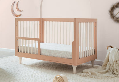 Stylish peach-colored crib in a serene nursery setting with decorative moon wall art and cozy accents.