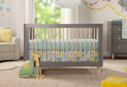 A cozy nursery room featuring a grey crib with blue and yellow bedding, accompanied by plush giraffe and elephant toys, against a backdrop of a softly lit window and cheerful decorations.