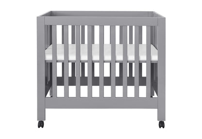Modern gray baby crib on wheels with a visible white mattress.
