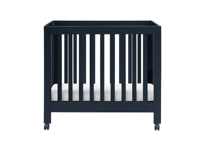A modern dark blue crib on wheels with a white mattress, isolated on a white background.