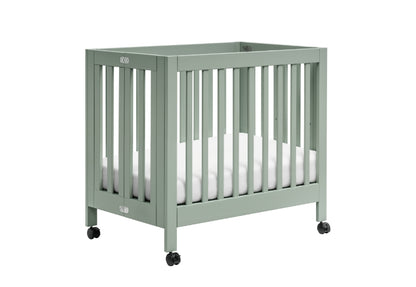 Green baby crib on wheels with a white mattress,