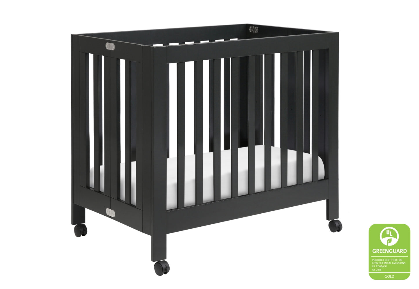 Black baby crib on wheels with a white mattress, showing a Greenguard Gold certification badge.