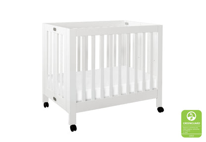 White modern baby crib on wheels with a certification badge displaying "GREENGUARD GOLD."