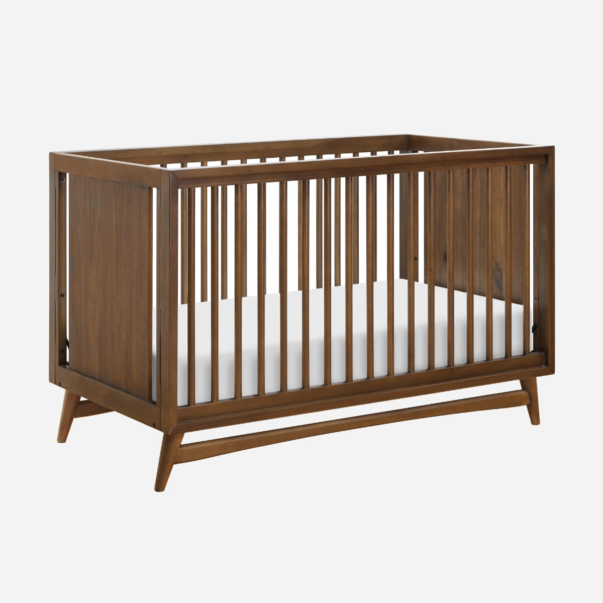 Classic wooden crib with slatted sides and a white mattress, isolated on a plain background.