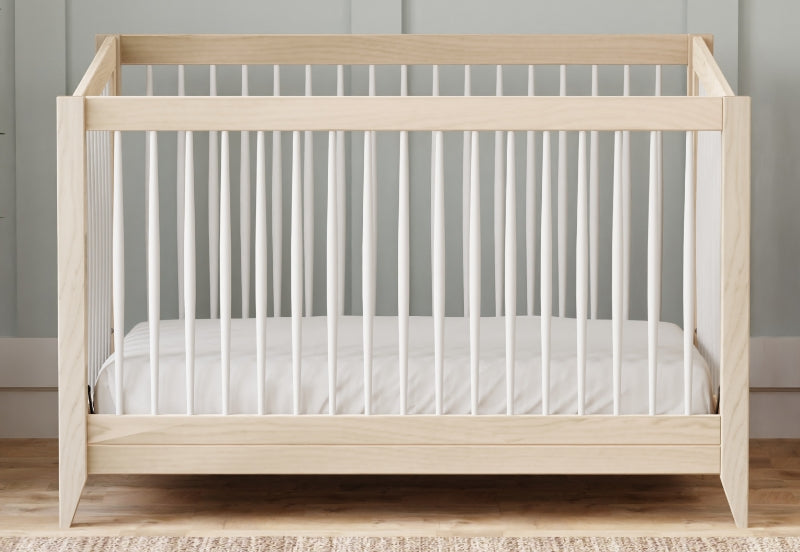 A modern wooden baby crib with a white mattress set against a gray wall. 999-8503-WWH