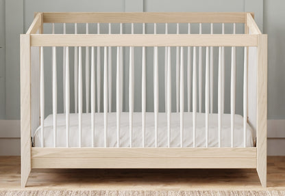 A modern wooden baby crib with a white mattress set against a gray wall. 999-8503-WWH
