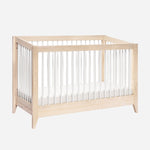 The Babyletto Sprout Convertible Crib features a simple, modern design with a light wood frame, white vertical slats, and a white mattress, making it an ideal 4-in-1 nursery piece for any space.