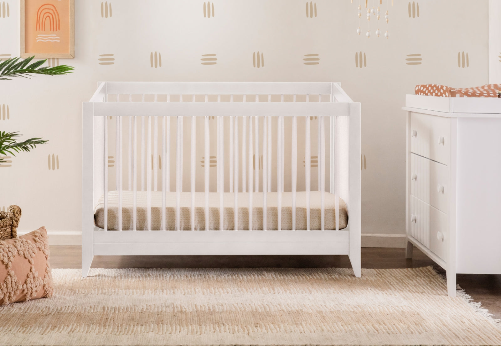 Modern nursery featuring a white crib, dresser, and minimalistic decor in neutral tones. 999-8503-WHT