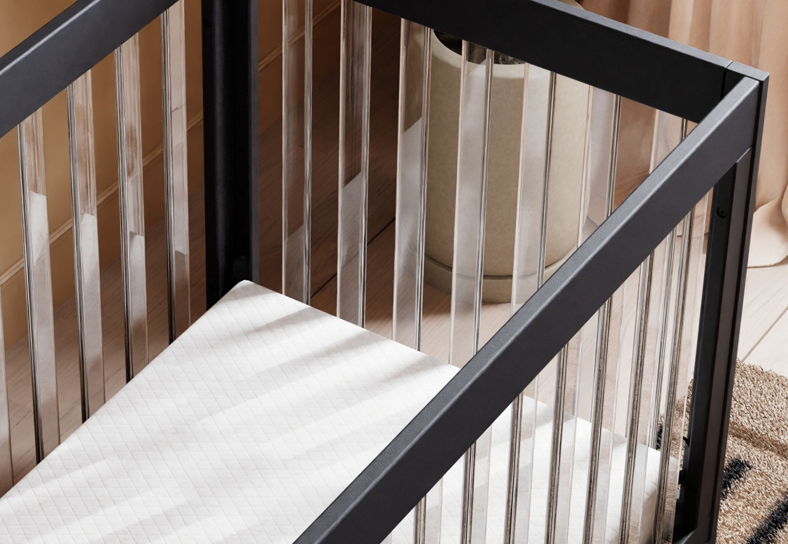 Close-up view of a black-framed baby crib featuring a breathable, patterned mattress from Newton Baby.