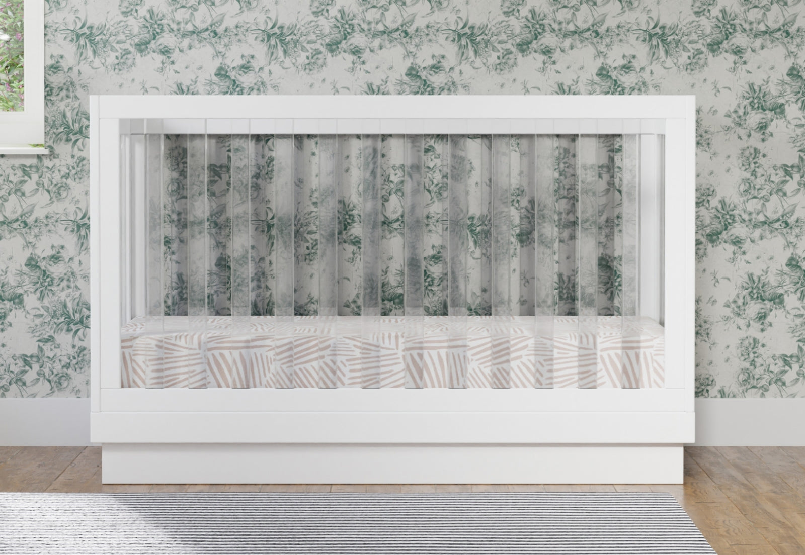 White modern baby crib with transparent safety railings and a mattress in a room with floral wallpaper. 999-8500-WHT