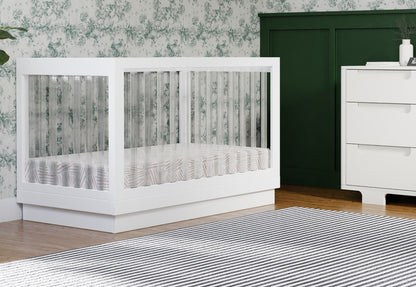 Modern white crib in a stylish nursery with floral wallpaper and dark green accents.