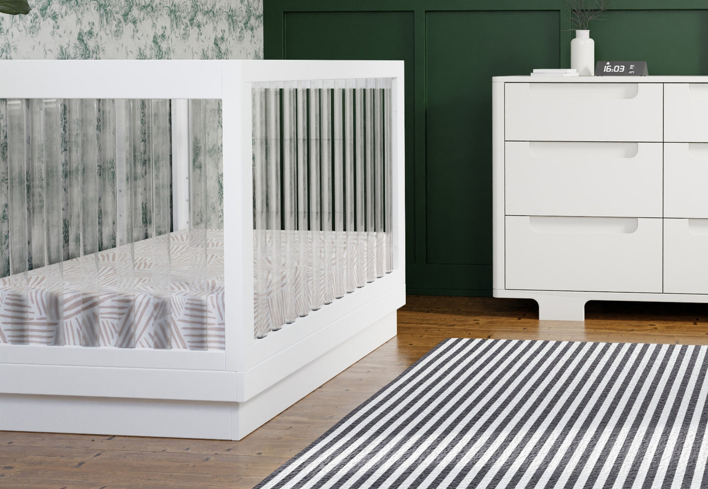 Modern nursery featuring a stylish white baby crib beside a sleek white dresser, complemented by a green wall and a striped rug.