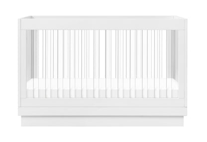 Modern white baby crib with vertical slats and a mattress visible, isolated on a white background.