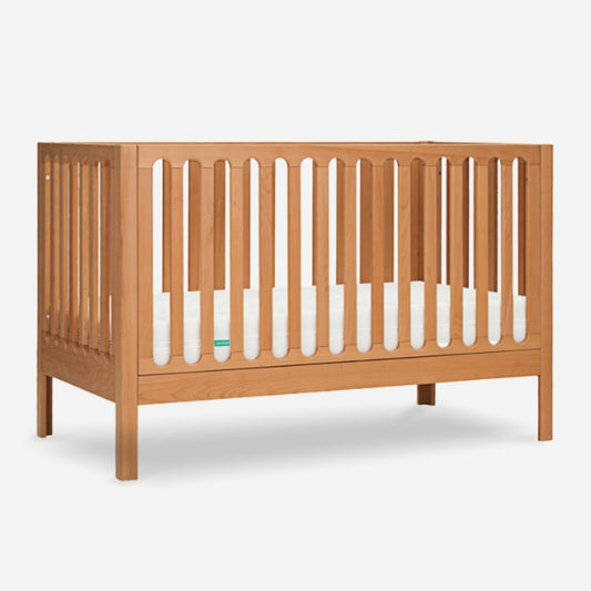 Wooden baby crib with visible mattress and slatted sides on a white background. skip