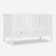 White baby crib with slatted sides and a visible mattress, isolated on a gray background. skip