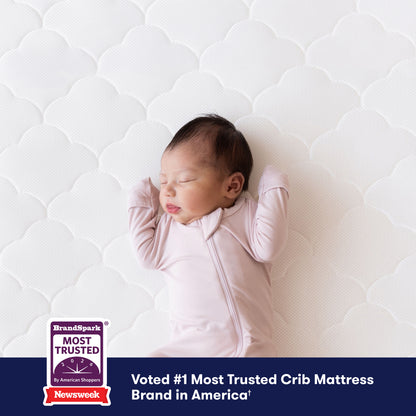 A baby sleeping on a Newton Baby Crib Mattress with a repeating quatrefoil pattern and a badge stating Voted #1 Most Trusted Crib Mattress Brand in America. 500-1000-WHT-ST