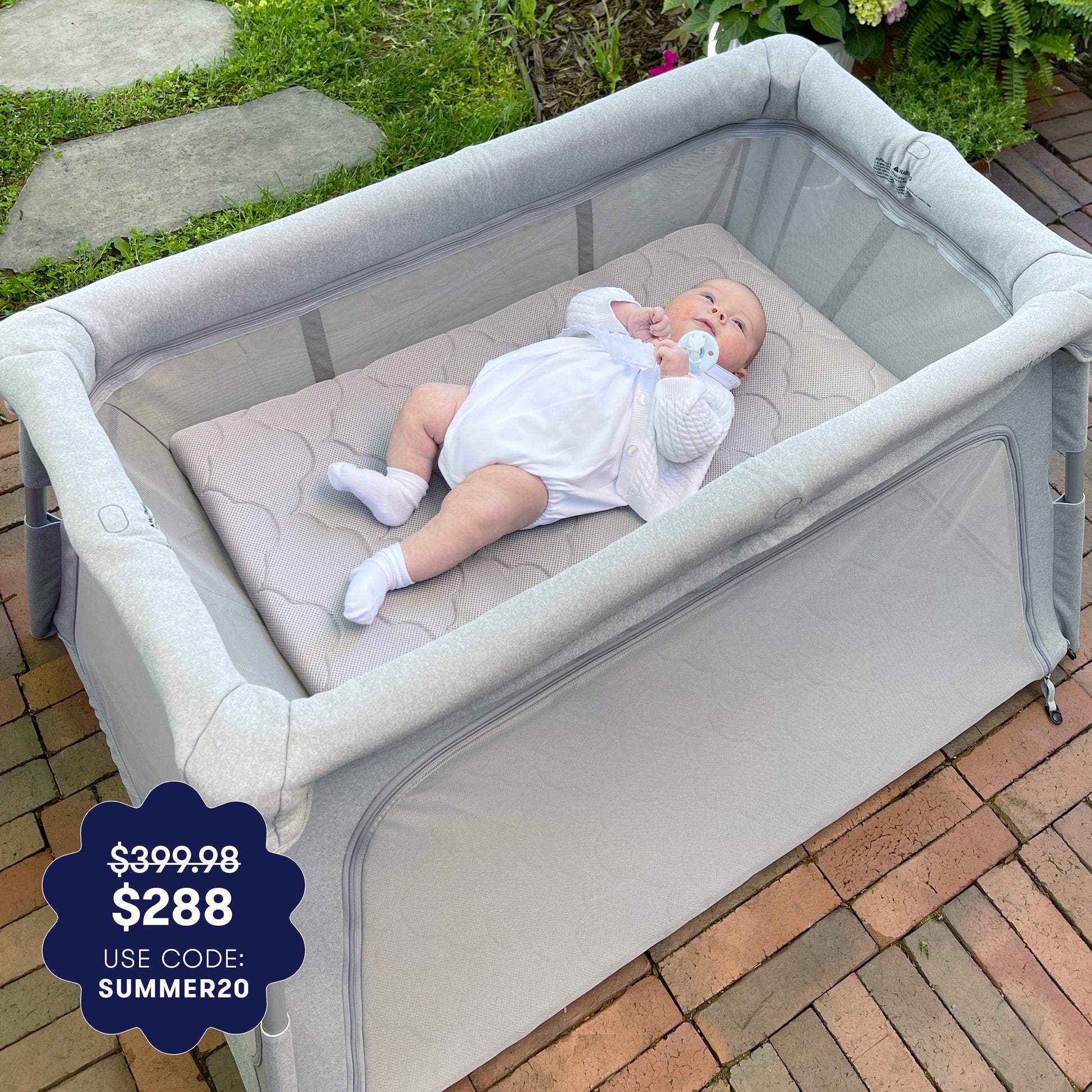 Baby in a gray crib with a price tag overlay on a patio. 999-5010-GRY
