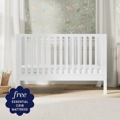 A white Newton Galileo Convertible Crib by Newton Baby, complete with a mattress, stands in a bright nursery decorated with nature-themed wallpaper. A badge in the corner reads: “Free ESSENTIAL CRIB MATTRESS.”.
