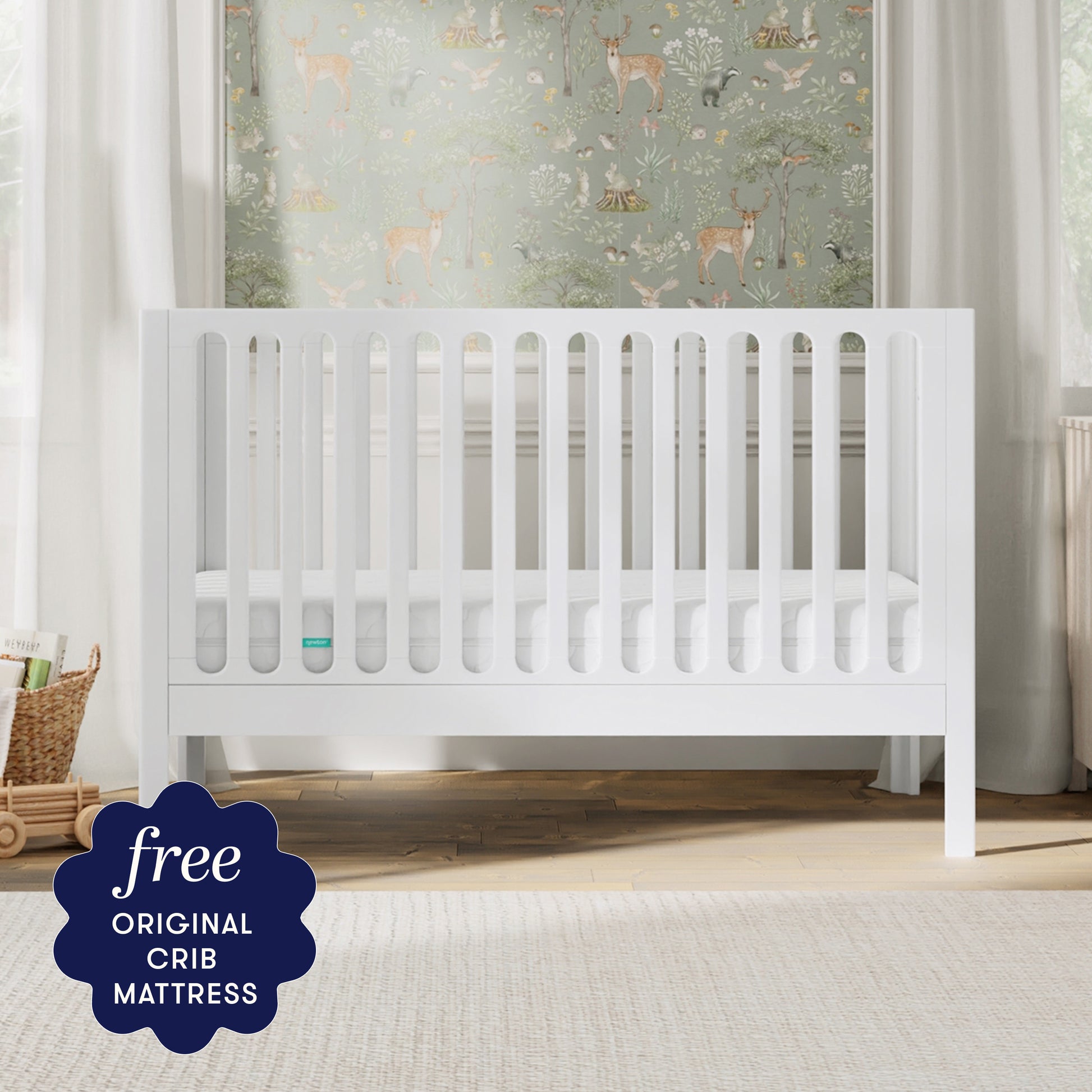 The Newton Galileo Convertible Crib by Newton Baby, made of modern beech wood, sits in a softly lit nursery with animal-themed wallpaper. A dark blue label notes: "Free ORIGINAL CRIB MATTRESS" and easy toddler bed conversion.