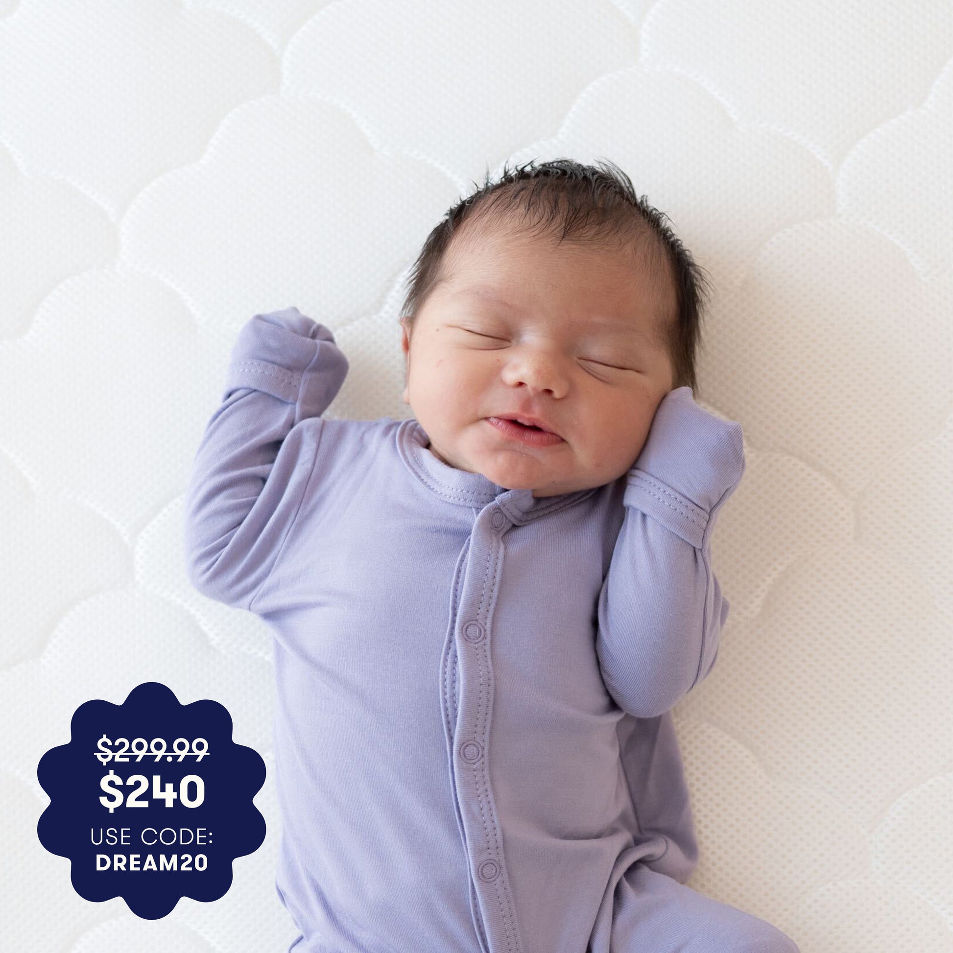 A newborn baby in a lavender onesie sleeps on the Newton Baby Crib Mattress, which features a white, breathable design with a quilted removable cover. A blue price tag reads: $299.99, $240, use code: DREAM20. 