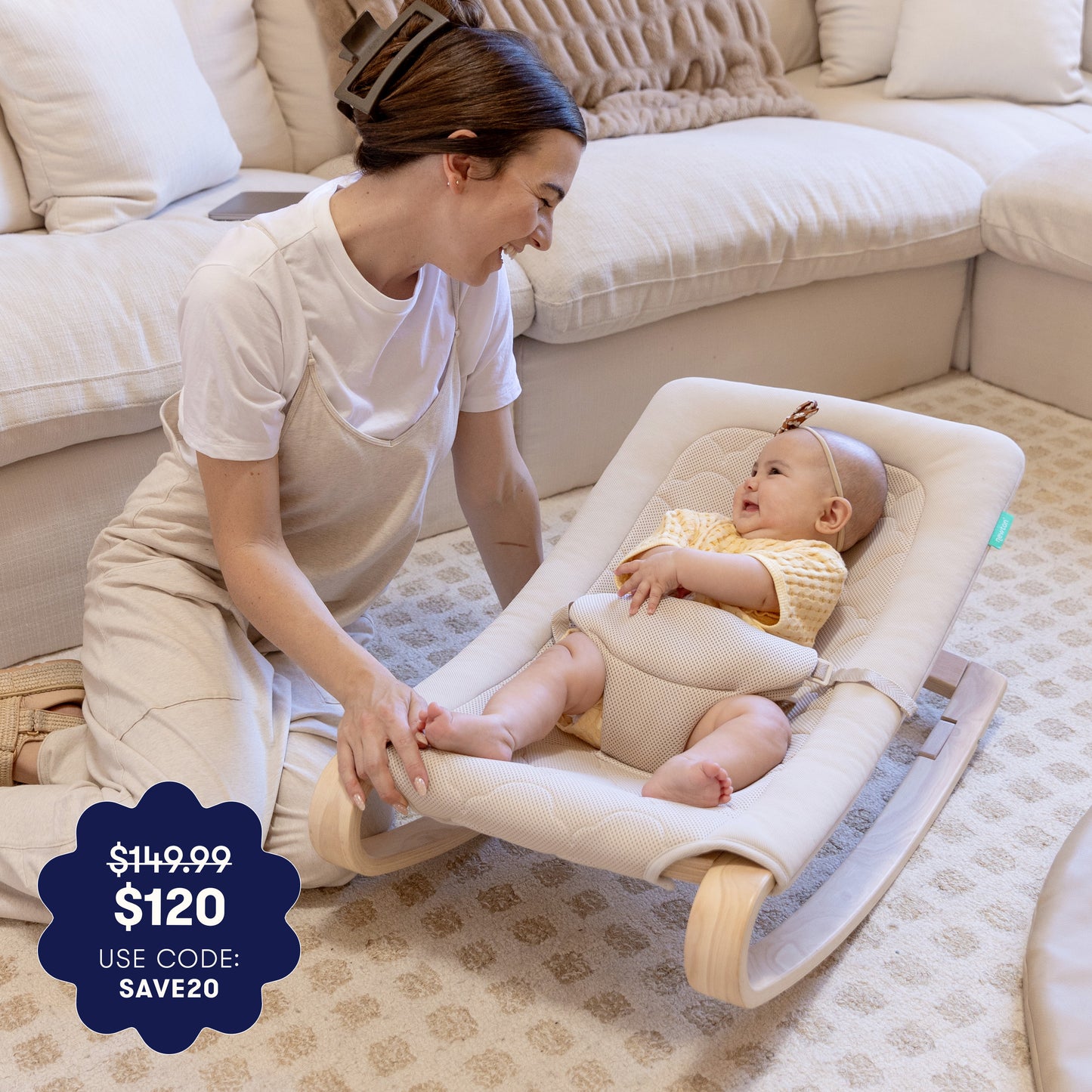 A smiling woman kneels by a happy baby in the Newton Baby Rocker by Newton Baby, enjoying a cozy, carpeted living room. Overlay text highlights the price drop from $149.99 to $120 with code SAVE20.