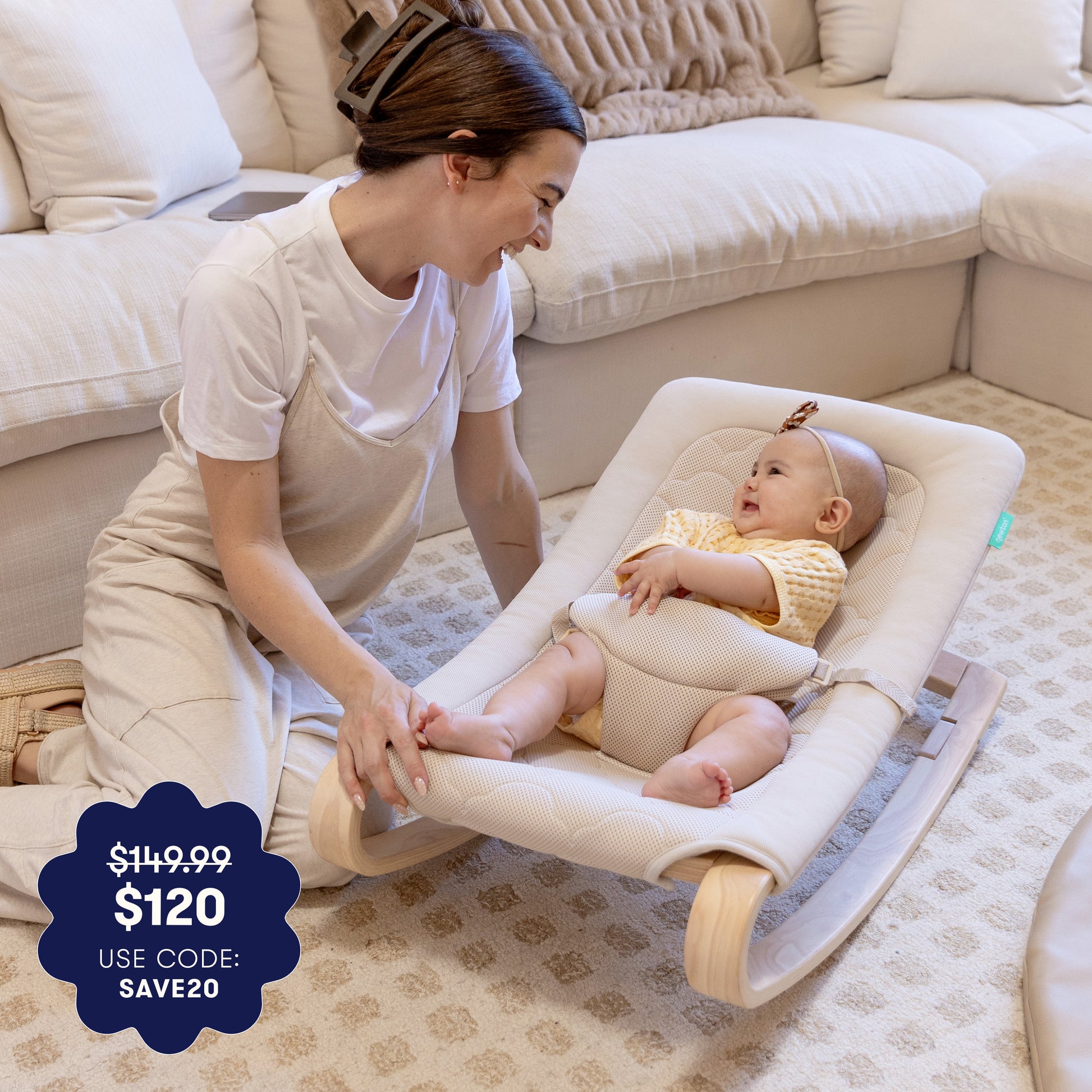 A smiling woman kneels by a happy baby in the Newton Baby Rocker by Newton Baby, enjoying a cozy, carpeted living room. Overlay text highlights the price drop from $149.99 to $120 with code SAVE20.