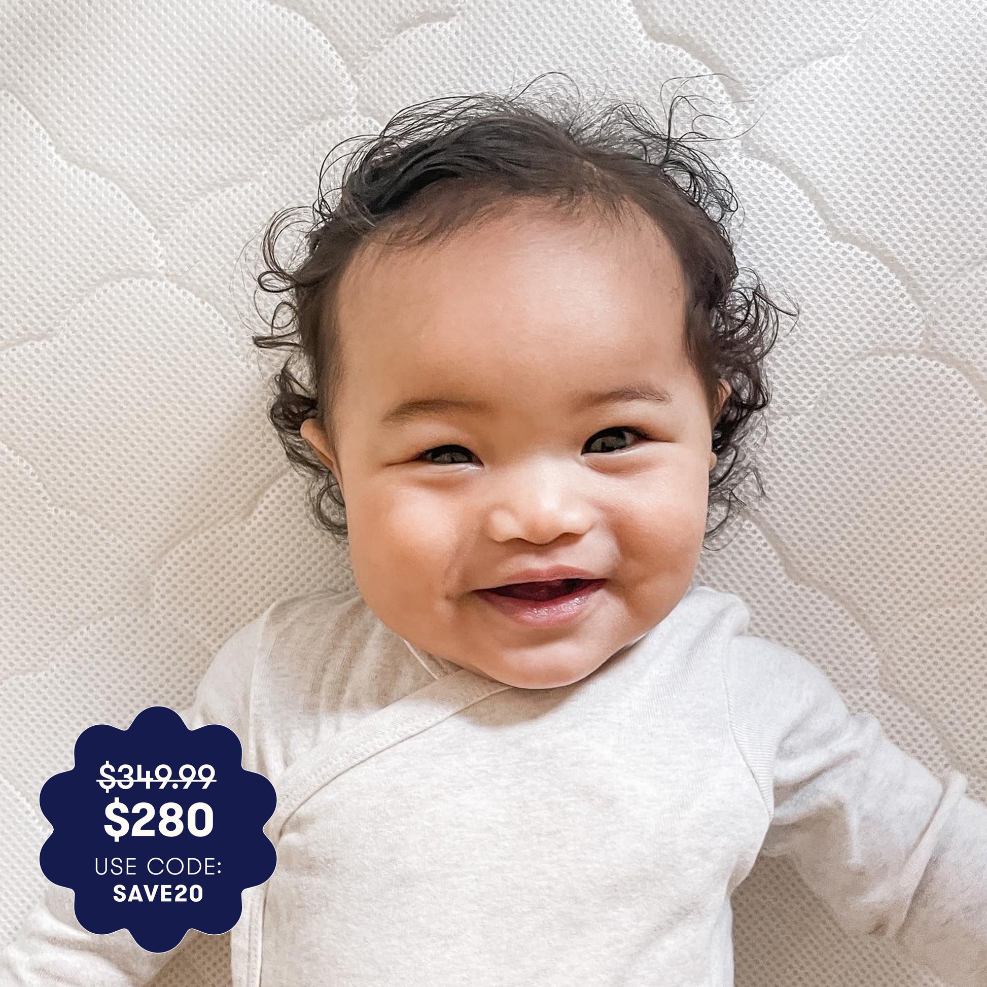 A smiling baby in a light outfit lies on a Newton Baby Waterproof Crib Mattress with a washable cover. Blue price tag graphic: $349.99 $280 USE CODE: SAVE20.