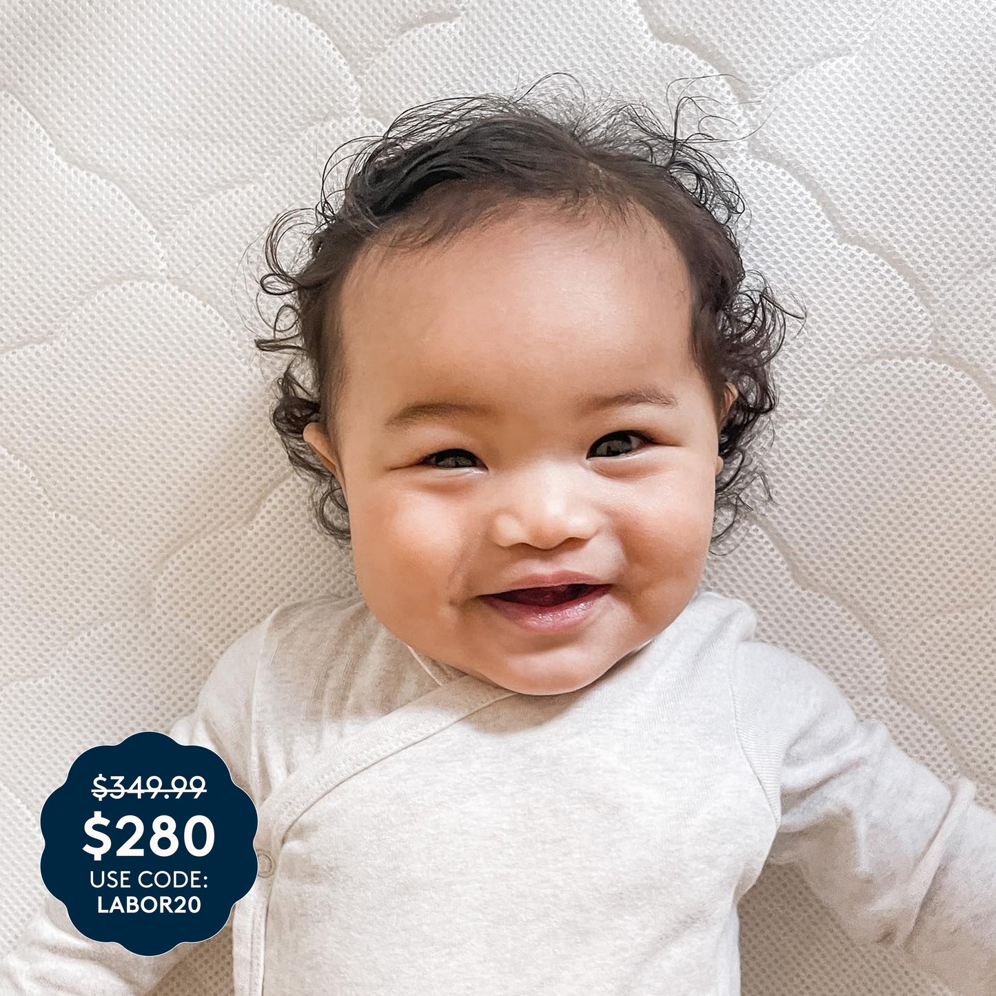 A smiling baby in a light outfit lies comfortably on a textured white surface, resting on the Newton Baby Waterproof Crib Mattress with a breathable design and washable cover. In the corner, price tags display $349.99 and $280, along with the promo code: LABOR20.