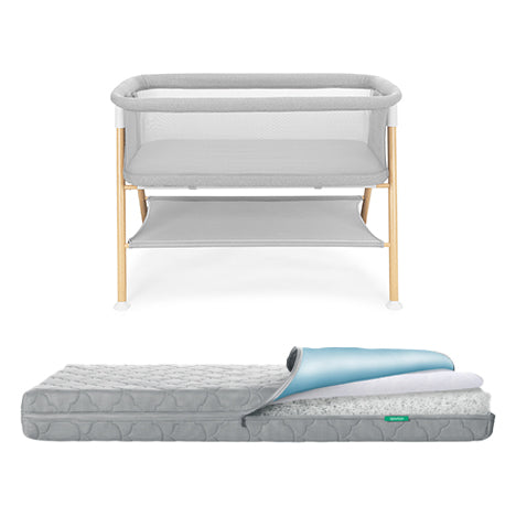 Grey Newton waterproof mattress next to essential bassinet on a white background