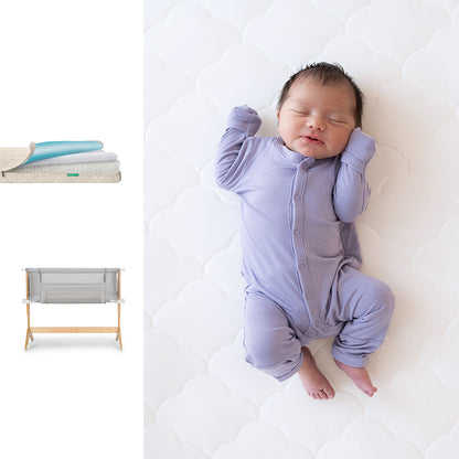 A newborn in a lavender onesie rests on the Newton Baby Bassinet & Bedside Sleeper + Waterproof Mattress. To the left are images of folded bedding and the gray sleeper with wooden legs.