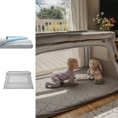 A baby in a light purple outfit crawls inside the Newton Baby Bundle 7 BFCM gray mesh deluxe travel crib with a breathable mattress, alongside a stuffed bunny and rainbow stacking toy, near a sunny window. 1001-gry-5100