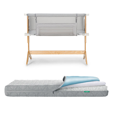 A Newton Baby Bundle 5 BFCM features a wooden-framed baby bassinet with light grey mesh sides placed above a grey patterned crib mattress with a removable top layer partially rolled back.