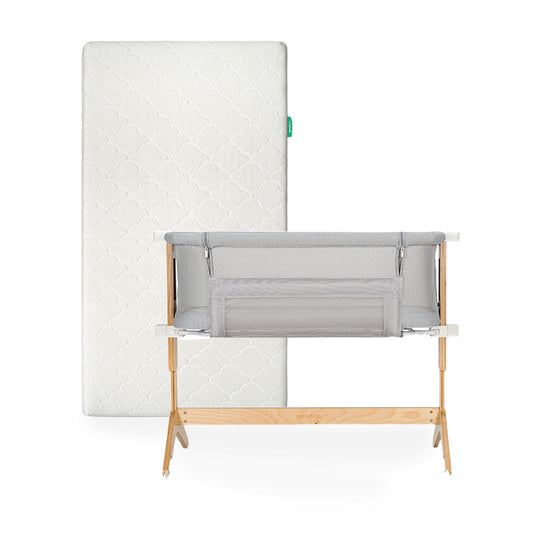 The Newton Baby Bundle 3 BFCM features a white washable crib mattress with a subtle patterned cover standing upright behind a gray breathable bassinet bedside sleeper with a light wooden frame.