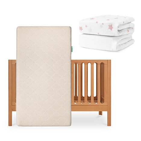 The Newton Baby Galileo Crib stands upright with the Original Crib Mattress; nearby are a folded white crib sheet with pink stars and a plain organic cotton sheet from the Galileo collection. skip