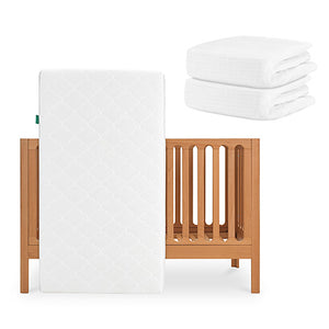 The Galileo Crib, Original Crib Mattress & Sheets by Newton Baby are shown: the convertible crib with a white, breathable mattress stands upright, while two folded organic cotton sheets are stacked beside it against a plain white background. skip