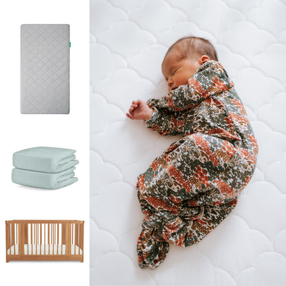 A baby in a floral swaddle rests on the Newton Baby Original Mattress. To the left, images show the Nest Convertible Crib and two folded breathable organic cotton sheets—all part of the Nest Convertible Crib, Mattress & Sheets set. 111-8420-CST-1000-GRY-SNS
