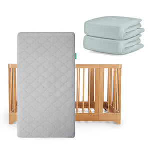 The Newton Baby Nest Convertible Crib has vertical slats and is paired with an Original Mattress in a gray pattern and two folded light blue Breathable Organic Cotton Sheets.