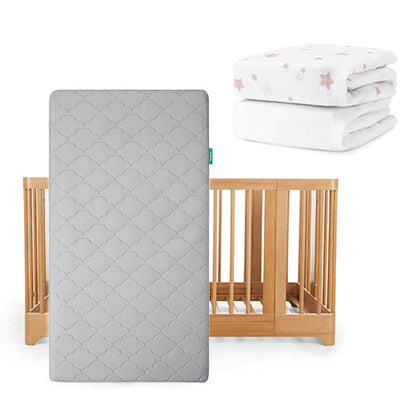 The Newton Baby Nest Convertible Crib, Original Mattress, & Sheets set features a wooden crib with a breathable mattress in gray and two folded crib sheets, including one white with pink stars.