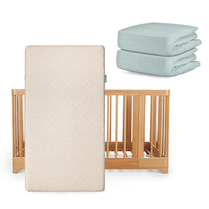 The Newton Baby Nest Convertible Crib with the Original Mattress is shown in light wood, paired with two folded light blue sheets—product set includes crib, mattress, and sheets.