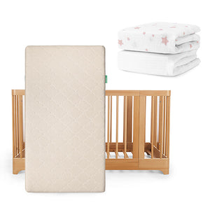 A Newton Baby Nest Convertible Crib with Original Mattress stands upright, with two folded breathable organic cotton crib sheets—one plain white, one with pink stars—positioned above and to the right.