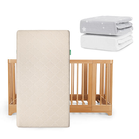 A Newton Baby Nest Convertible Crib with Original Mattress is propped upright, with two folded sheets—one gray with white stars and one solid white Breathable Organic Cotton Sheet—placed above and to the right.